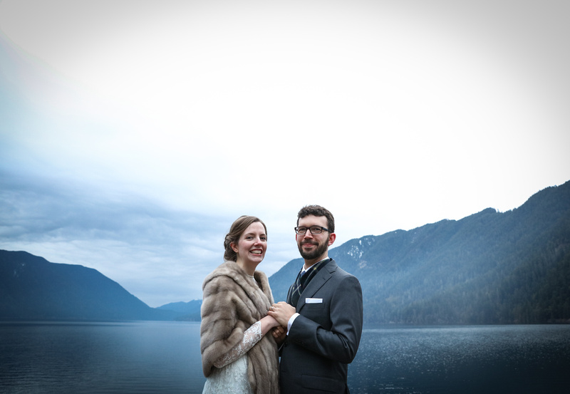 Wedding photography, a bride and groom smile with glee in front of a mountainside lake. 