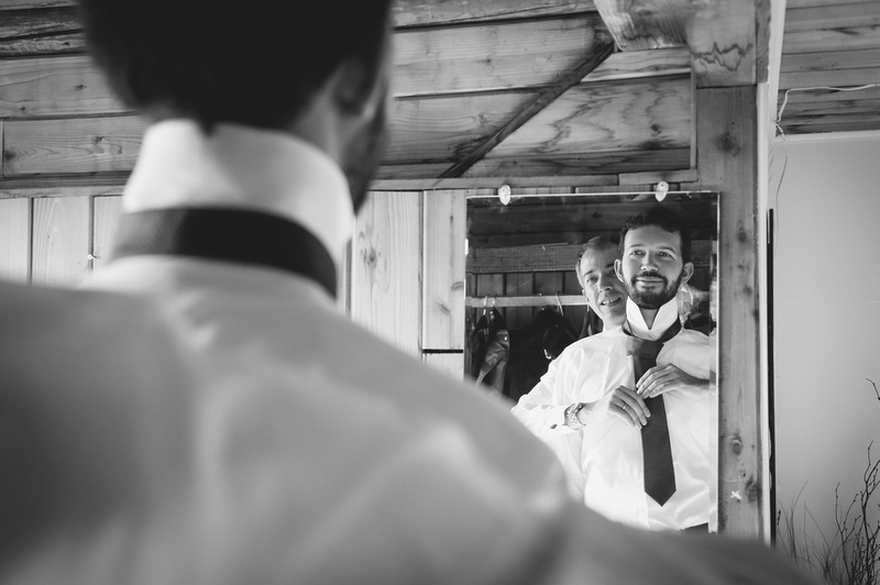 Wedding photography, a groom smiles as his brother fixes his wedding tie. 
