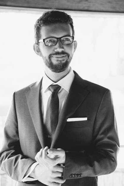 Wedding photography, a groom in glasses and a grey suit smiles. 