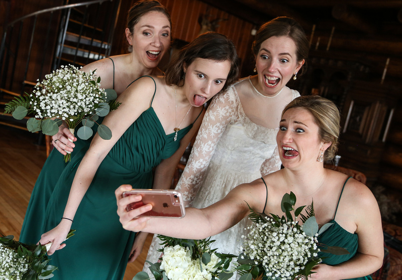 Wedding photography, a bride and her bridesmaids in green dresses take a silly selfie. 