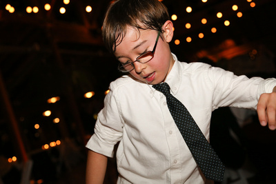 Wedding photography, a little boy dances in a white shirt with a black tie. 