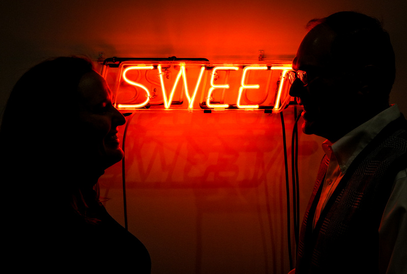 Engagement photography, a red, neon sign that says "sweet" with a couple in silhouette. 