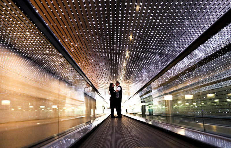 Engagement photography, a couple embraces in a tunnel filled with lights. 