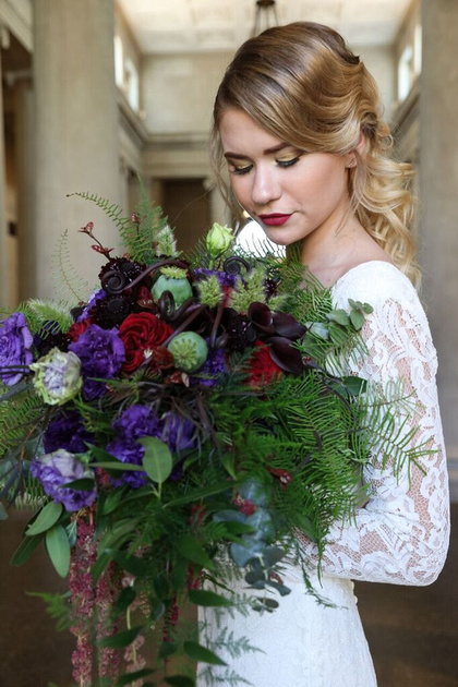 Bride holds massive flower bouquet of reds, purples and greens made by Flower Haus Guys