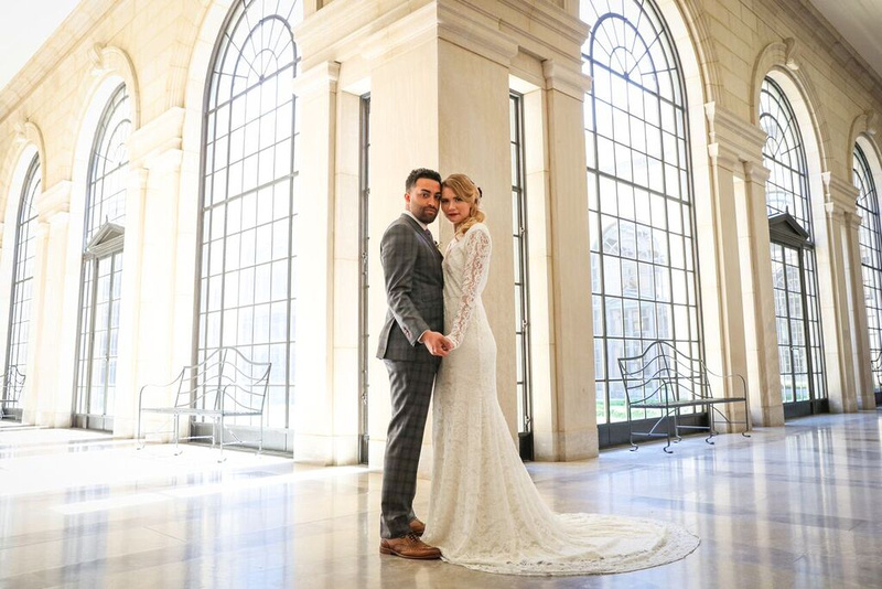 Bride and groom stand touching cheeks and looking at the camera, at the corner where two long hallways meet. Styled wedding shoot by photos by kintz at the baltimore museum of art