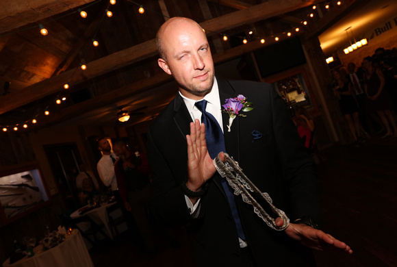 Wedding photography, the groom playfully looks at the camera as he preps to toss the garter. 