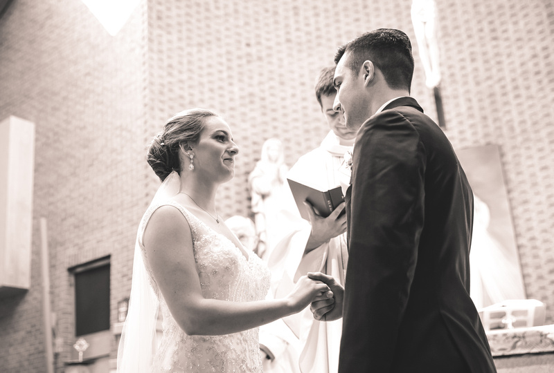 Wedding photography, a bride and groom gaze lovingly into each other eyes. They are holding hands in front of the alter. 