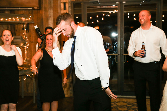 Wedding photography, a groomsman dances dramatically. The groom is smiling behind him. 