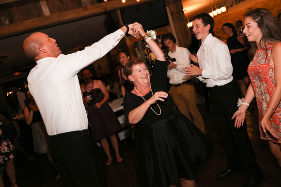 Wedding photography, the groom dances with the mother of the bride who is smiling.