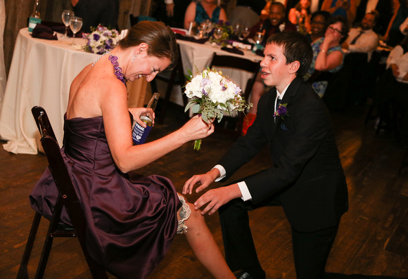 Wedding photography, a young man awkwardly puts the garter on the winner of the bouquet toss. 