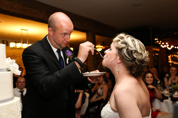 Wedding photography, the groom feeds his bride a bite of cake. She has her eyes closed with happiness. 