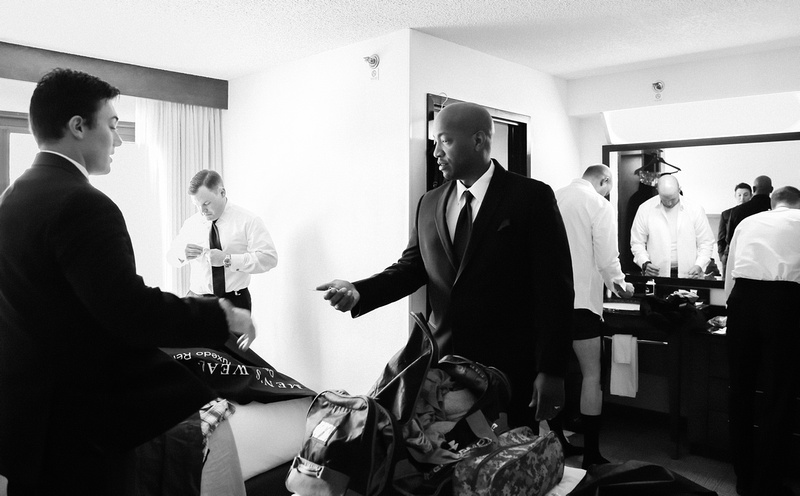 Wedding photography, a groom and his groomsmen get dressed in their hotel room. 