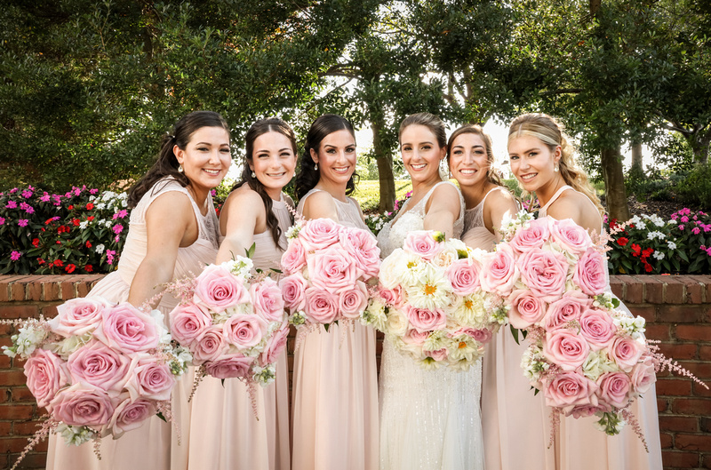 Wedding photography,  a bride and bridesmaids in pink dresses hold out their pink bouquets. 
