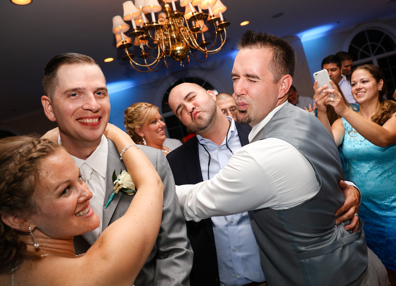 Wedding photography, a bride and groom smile on the dance floor while their friends make kissy faces at them. 
