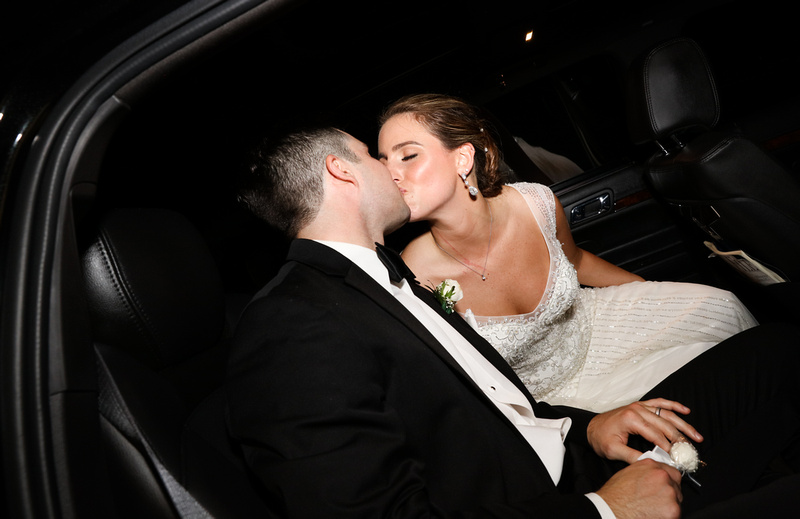 Wedding photography, the bride and groom kiss in their limo. 