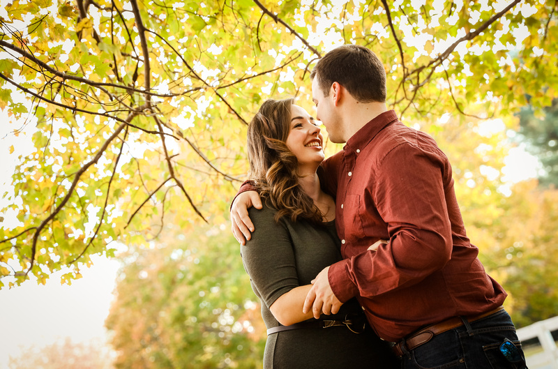Engagement photography: yellow leaves surround a couple who is embracing. 