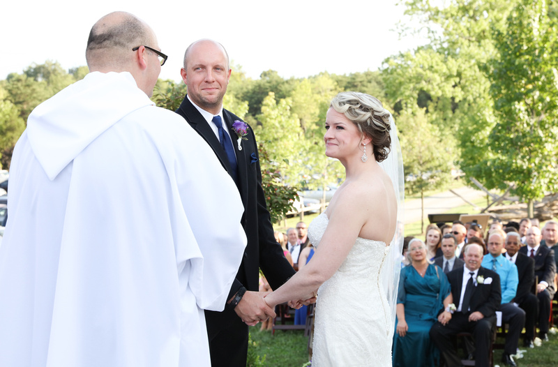 Wedding photography, a bride and groom hold hands and smile at the wedding officiant. 
