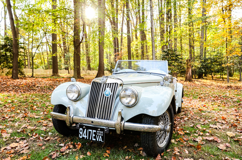 Engagement photography: an antique car sits in the fall woods. 