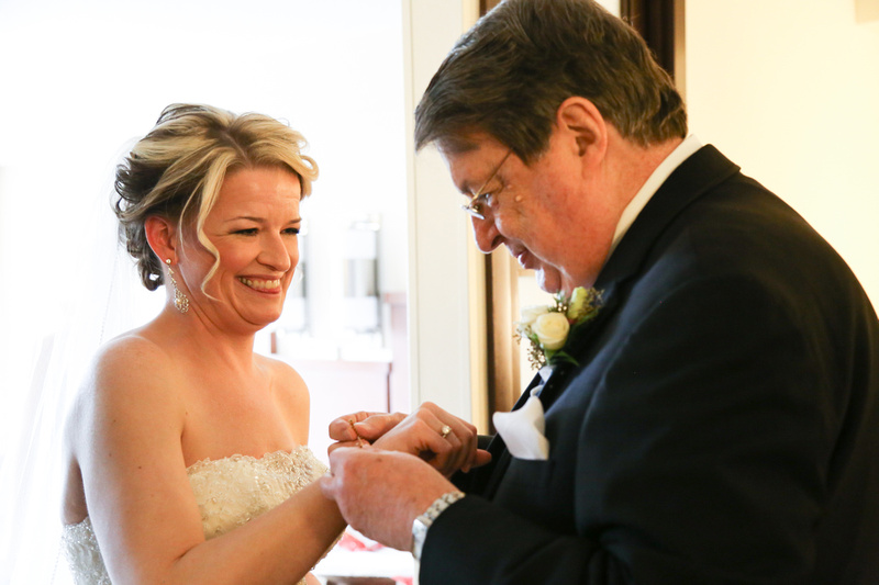 Wedding photography, a bride smiles with love as her father puts a bracelet on her wrist. 