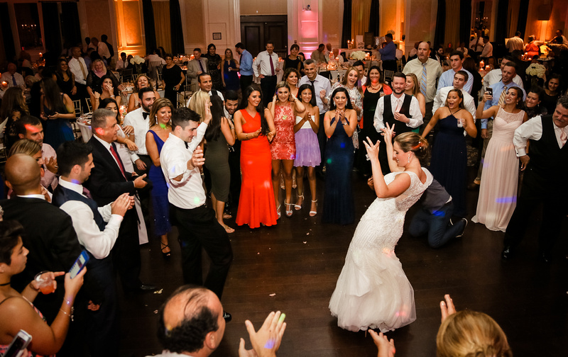 Wedding photography, the bride and groom dance with a big crowd surrounding them. 
