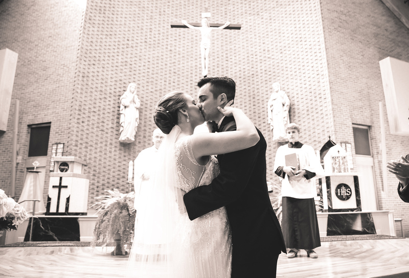 Wedding photography, the bride and groom share their first kiss in a Catholic Church. 