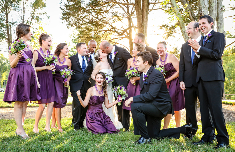 Wedding photography, the bridal party celebrates in the sunshine as the bride and groom share a kiss. 