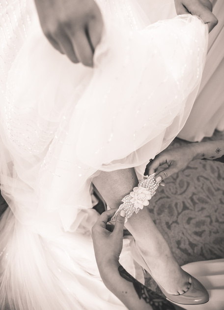 Wedding photography, a closeup of a garter being slipped onto the leg of a bride. 