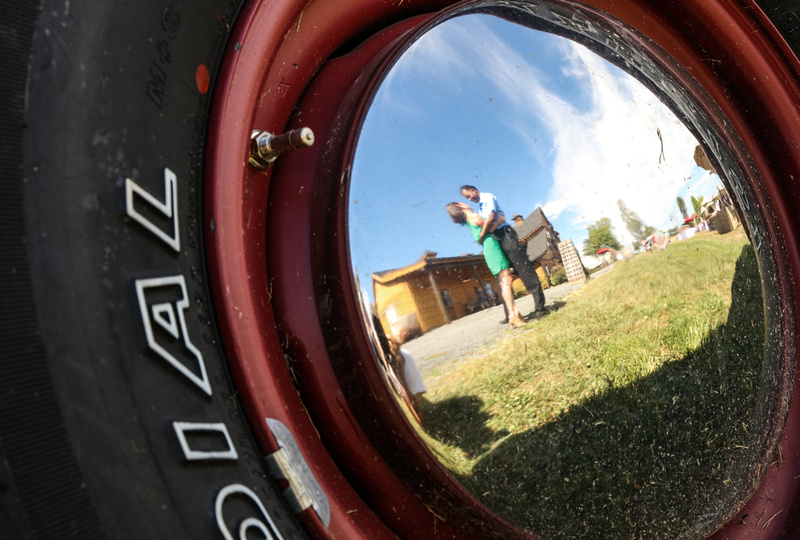Engagement photography: a photo of a couple's reflection in the wheel of a farm truck. They are embracing. 