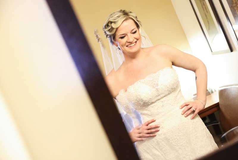 Wedding photography, a bride smiles in the mirror as she awaits her wedding ceremony. 