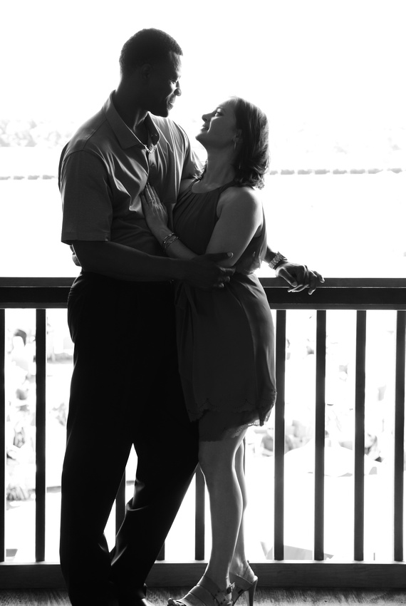 Engagement photography: a black and white photo of a couple leaning on a railing in a loving embrace. 