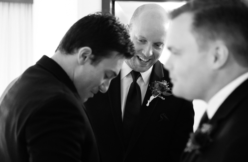 Wedding photography, the groom laughs while getting ready with his groomsmen. 