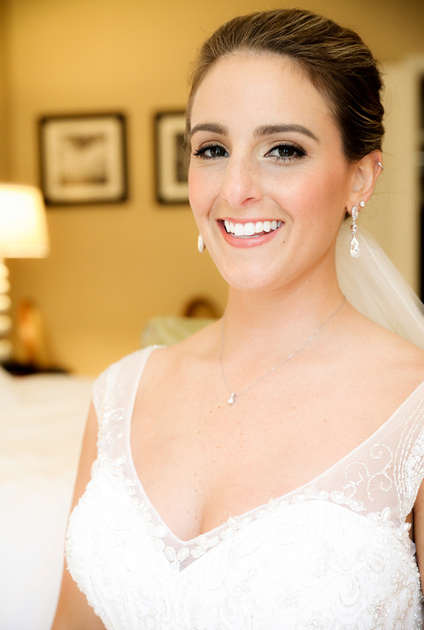 Wedding photography, a portrait of a beaming bride with dangling diamond earrings. 