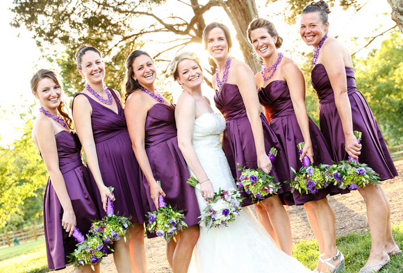 Wedding photography, a bride and her bridesmaids in purple dresses with white and green flowers. 