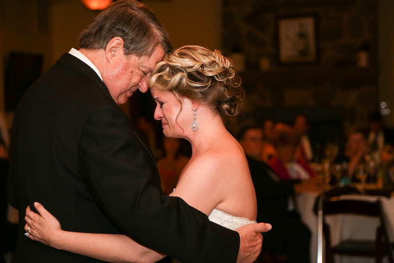 Wedding photography, a bride cries as she embraces her father on the dace floor. 